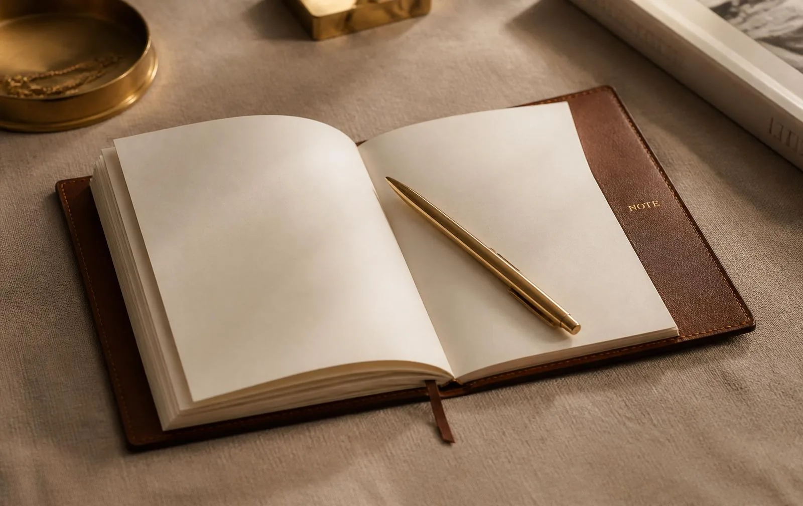 Open leather notebook with a gold pen on a warm surface